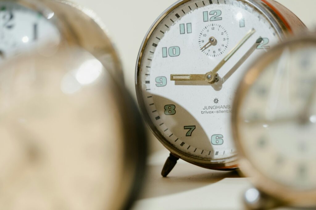 Several clocks blurred, one clock in focus, symbolising the doubt in the question Can I have a midlife crisis in my 30s?