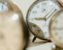 Several clocks blurred, one clock in focus, symbolising the doubt in the question Can I have a midlife crisis in my 30s?